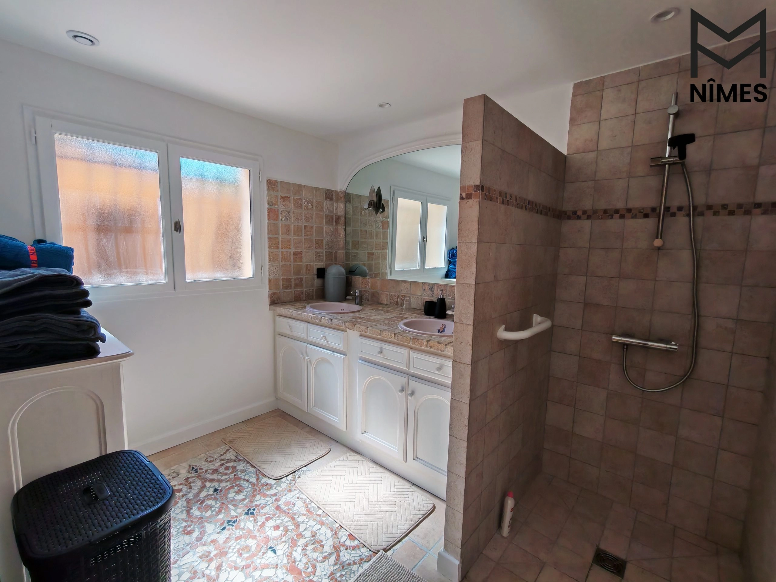 Salle de bain spacieuse avec douche à l’italienne et vasques artisanales peintes.