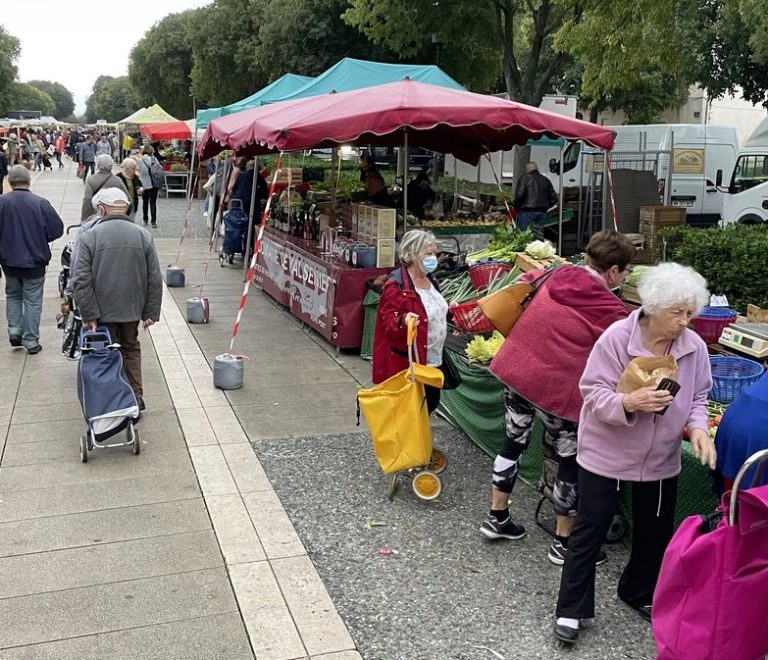 Marché local avec stands de fruits et légumes.