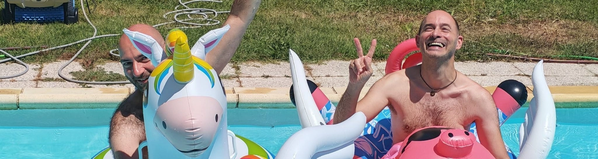 Deux hommes souriants dans la piscine avec bouées.