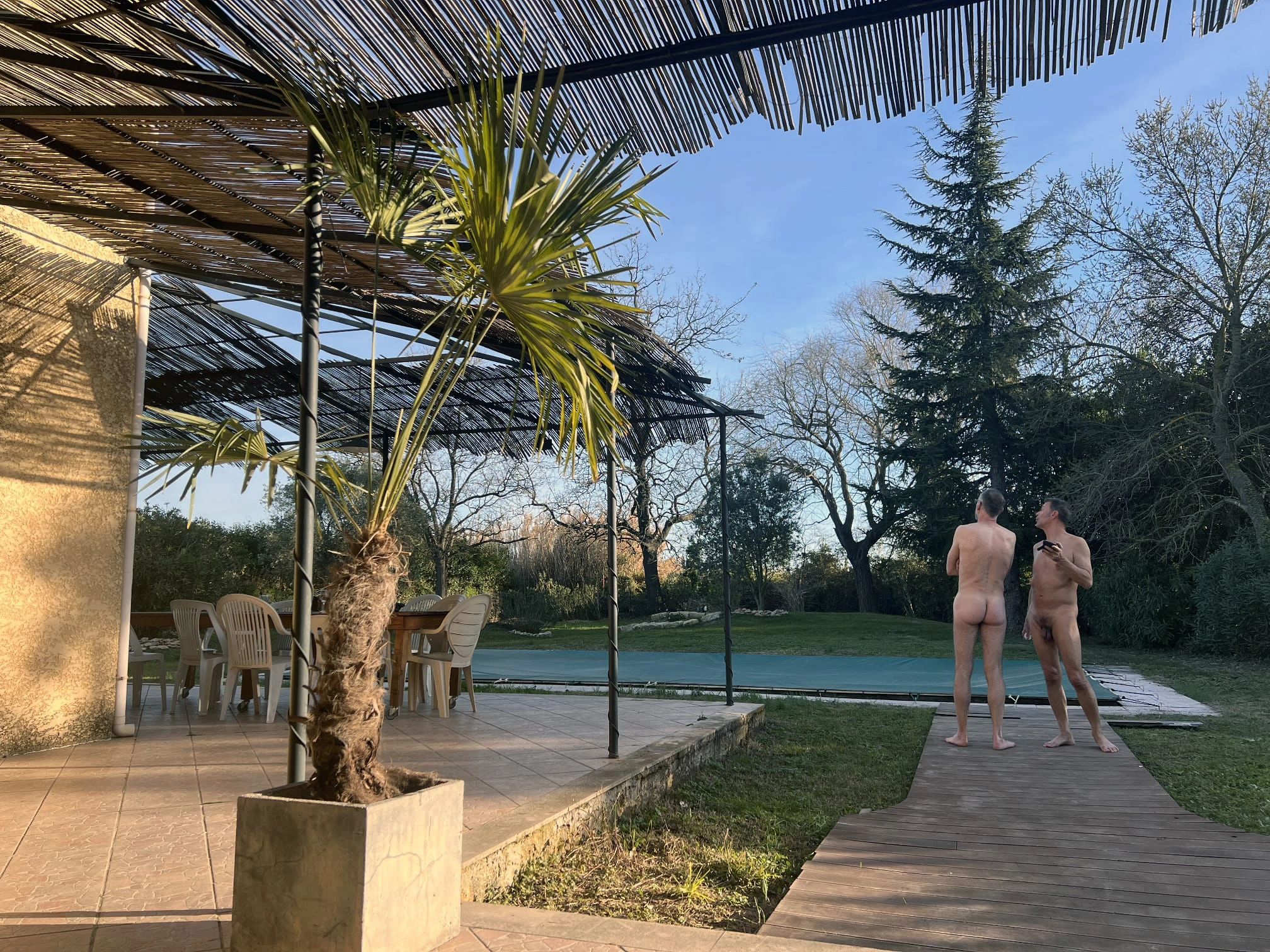 Deux personnes nues discutant devant la piscine.