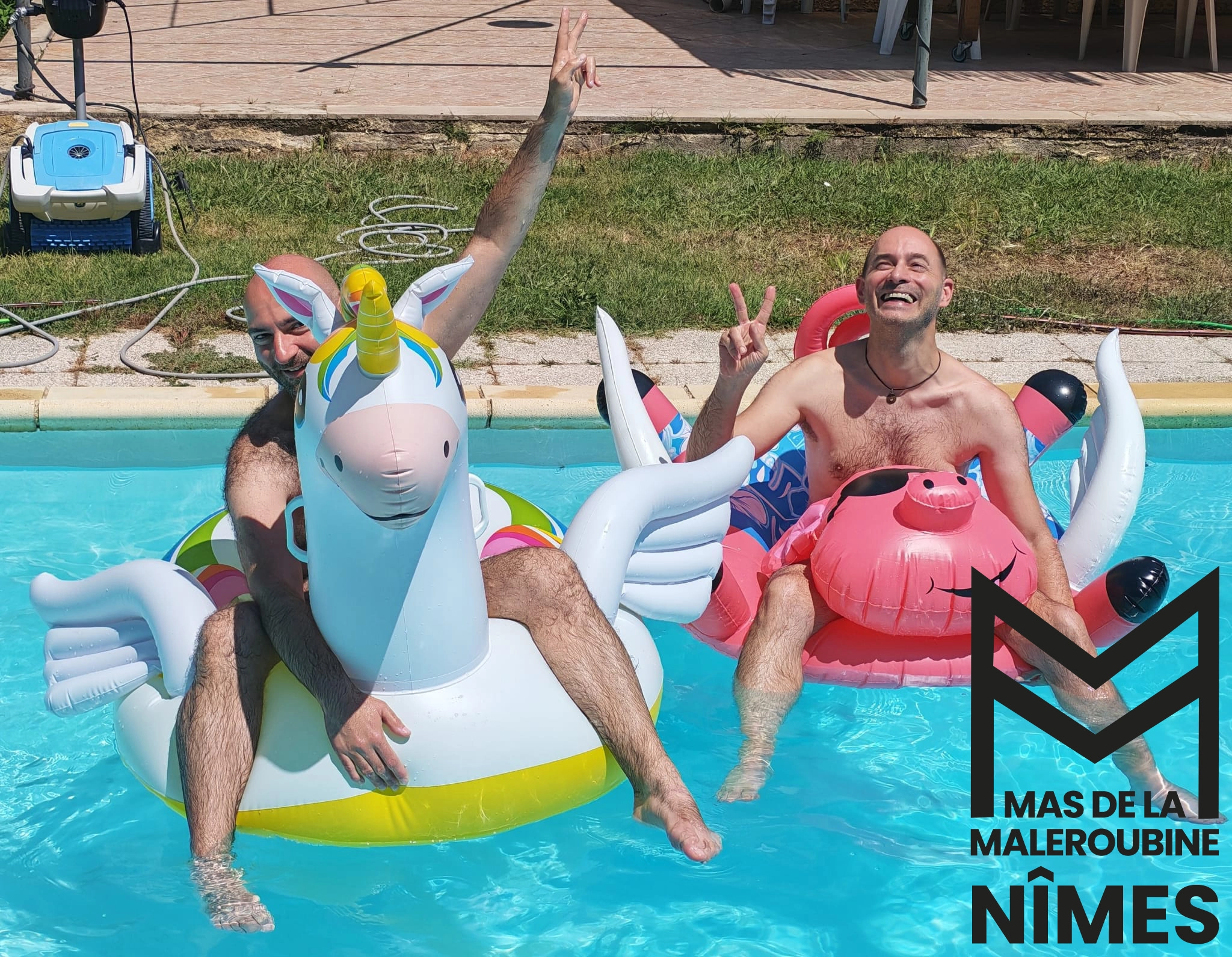 Deux hommes souriants dans la piscine avec bouées.